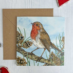 Irish Red Robin bird Christmas-themed card with watercolour painted decorative elements on a white surface