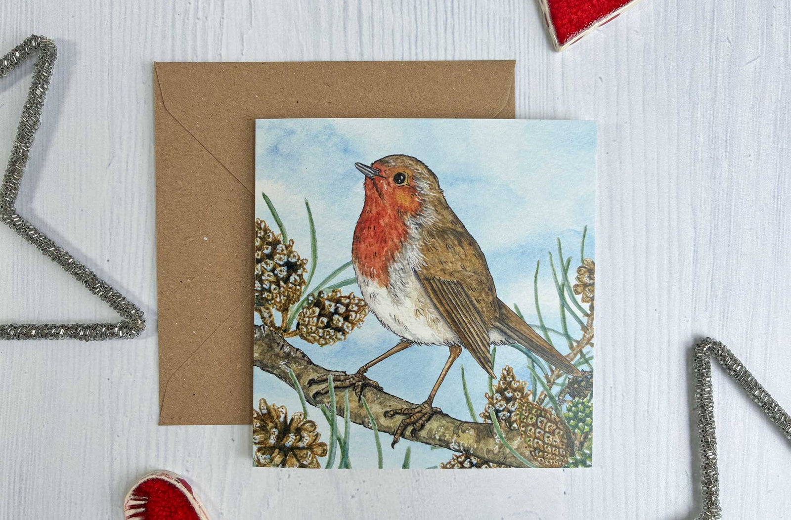 Irish Red Robin bird Christmas-themed card with watercolour painted decorative elements on a white surface