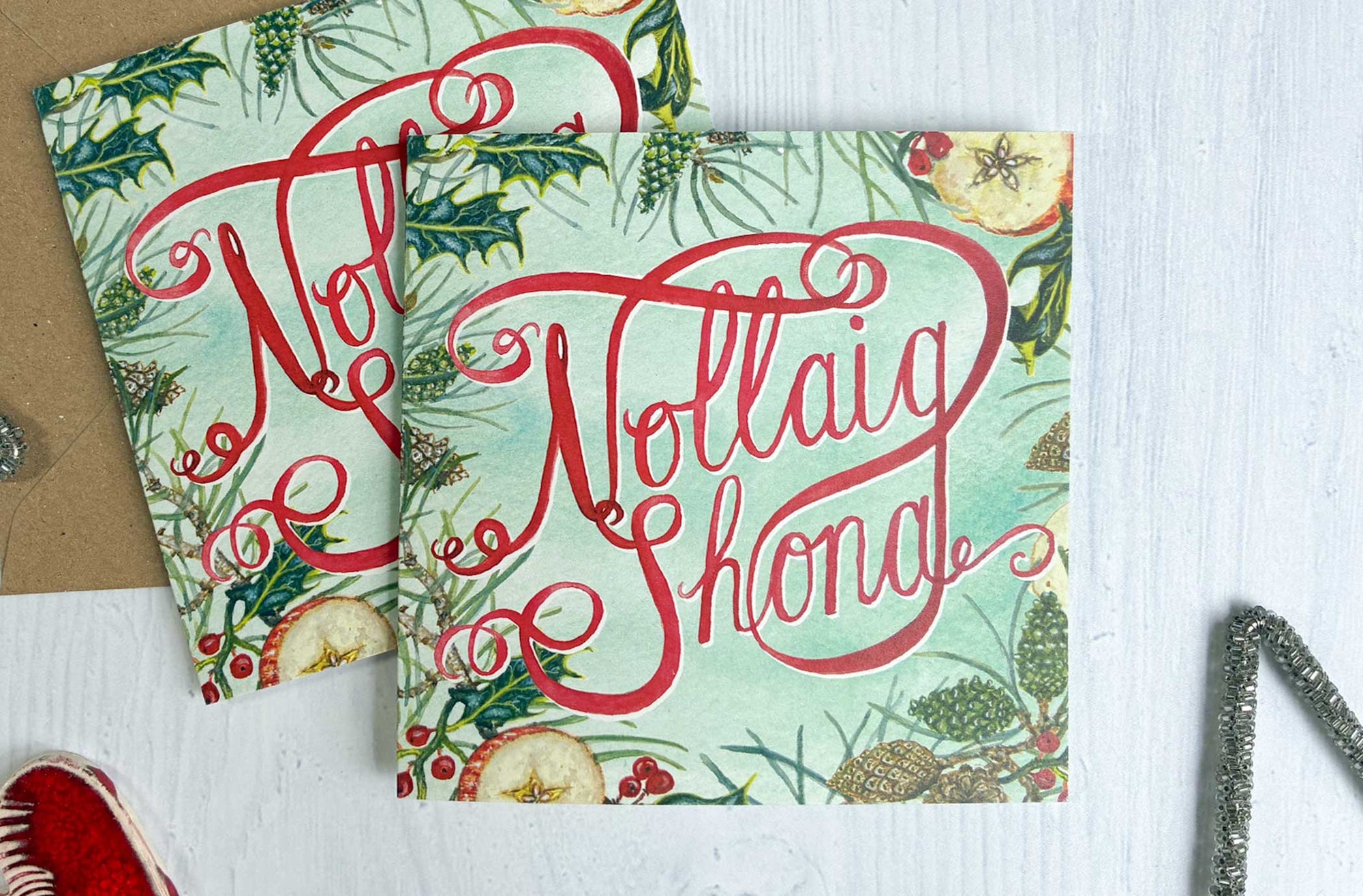 Nollaig Shona Irish Christmas-themed card with watercolour painted decorative elements on a white surface