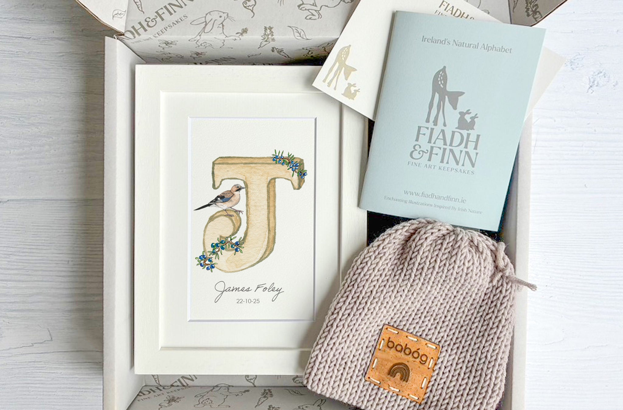 Gift set with a framed letter 'J', a book titled 'Fiadh & Finn', and a baby bootie gift box set
