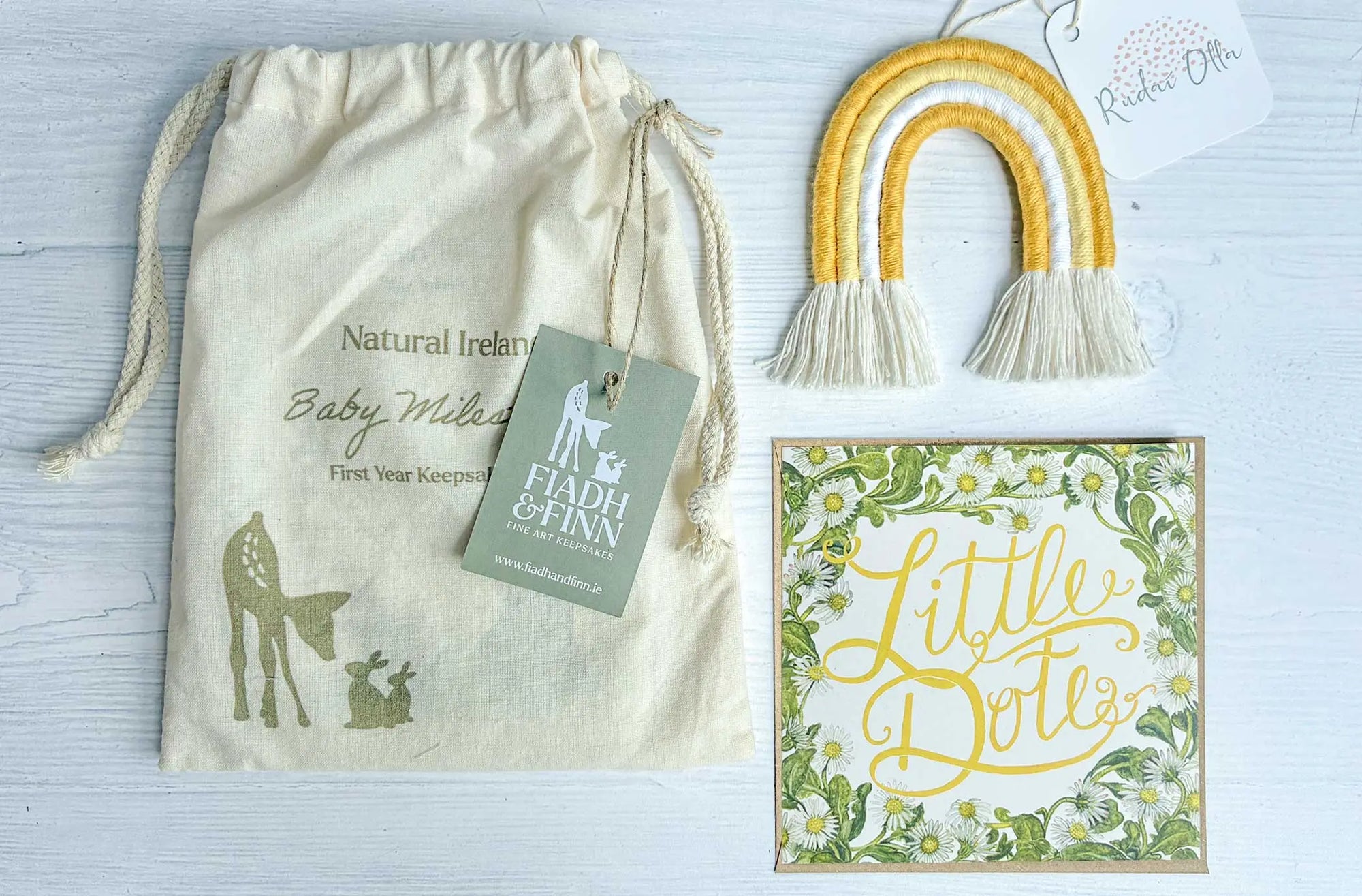 Baby gift set with drawstring bag, card, and 'Little Dolls' sign on a light background