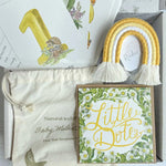 Baby shower gift set with decorative items and a box labeled 'Little Dotz' on a light wooden surface.