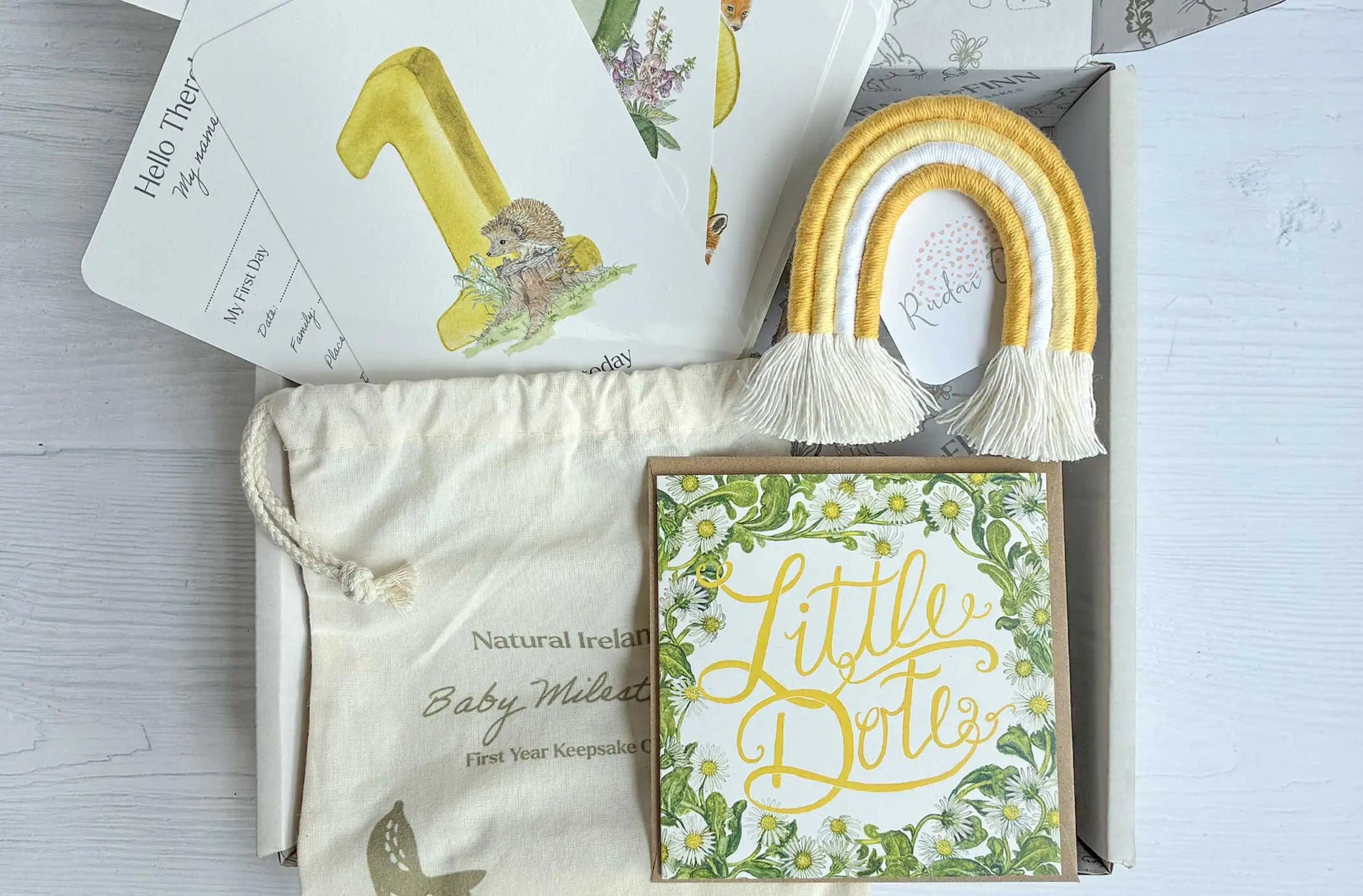 Baby shower gift set with decorative items and a box labeled 'Little Dotz' on a light wooden surface.