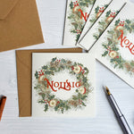 Christmas-themed cards with wreath designs and envelopes on a white surface.
