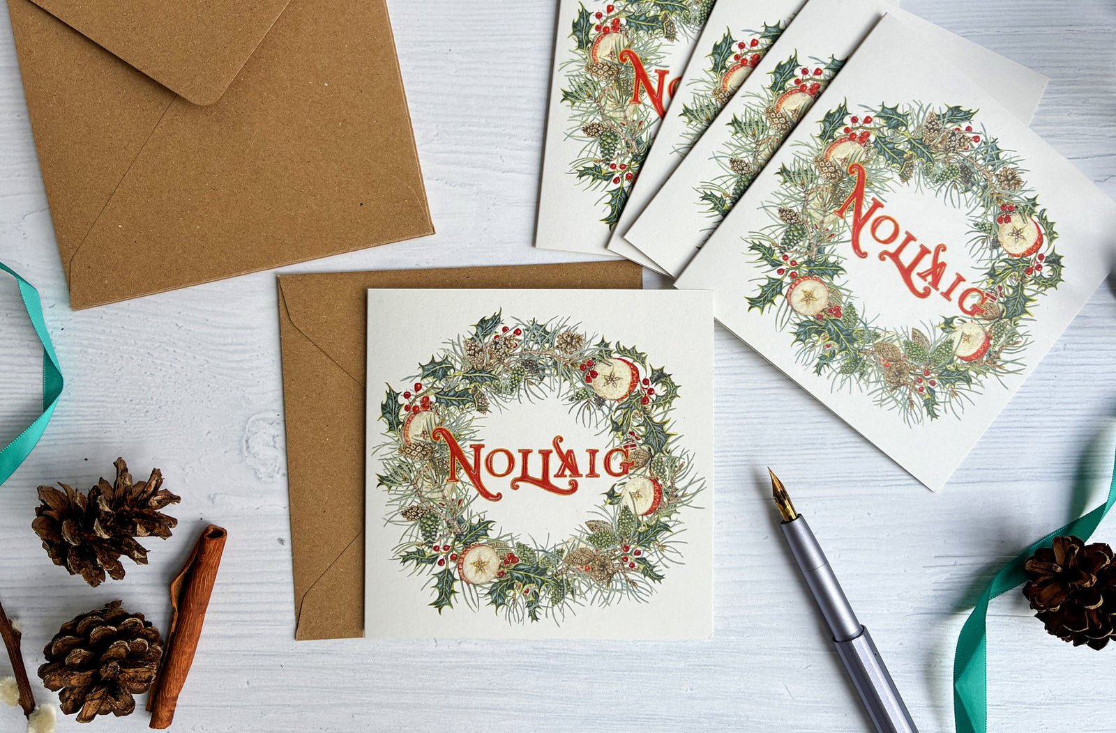 Christmas-themed cards with wreath designs and envelopes on a white surface.